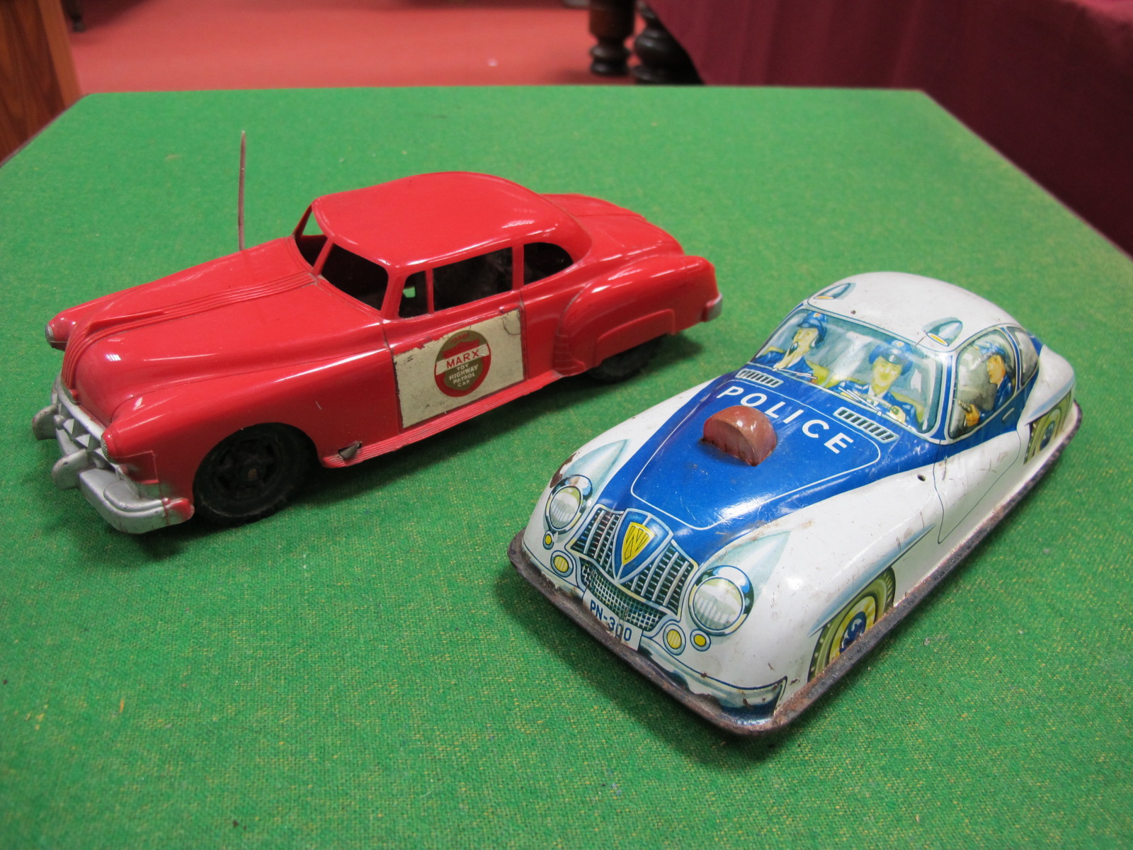 A 1950's Plastic Police Car, by Marx, friction drive, red plastic, 24cm long, plus a tinplate police