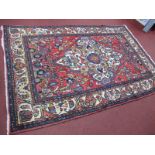 Middle Eastern Wool Rug, with cream central motif on scarlet ground, allover floral decoration and