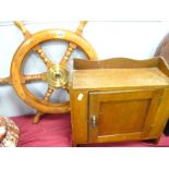 A XX Century Oak Wall Hanging Cupboard, with panelled door, together with a ship wheel with a