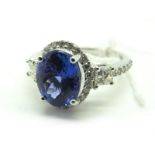 An 18ct White Gold Tanzanite and Diamond Cluster Ring, oval four claw set to the centre, within