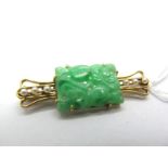A Carved and Pierced Jade Panel Brooch, on openwork bar with seed pearl highlights, stamped "15ct".