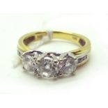 A Modern 18ct Gold Three Stone Diamond Ring, graduated claw set, between diamond set channel