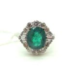 A Large Emerald and Diamond Set Dress Ring, oval four claw set to the centre, within shaped border