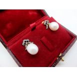 A Pair of Large Single Pearl Drop Earrings, each below openwork stylised bow set with brilliant