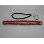 A Coral Coloured Twig Style Necklace, a jet coloured faceted bead necklace and an oval shell