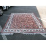 A Persian Kashan Tassled Wool Rug, with multi coloured flowers on rust ground, cream floral border