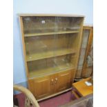 An Oak Book Cabinet, in the Ercol manner, having sliding glass upper doors over solid cupboard