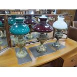 Three Early XX Century Brass Oil Lamps, (converted to electric) with glass shades, on circular