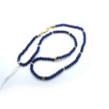 A Modern Lapis Lazuli Single Strand Uniform Bead Necklace, with faceted spacers, clasp stamped "750"