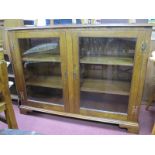 Oak Bookcase, with twin glazed doors on bracket feet, (bearing label Byethorpe Furniture Barlow