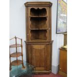 An Oak Double Corner Cupboard, with stepped cornice and two shaped shelves, the base with cupboard