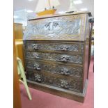 A XIX Century Carved Oak Bureau, the fall front with carved mythical beasts, four graduated