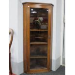 An Early XX Century Walnut Corner Cupboard, with a glazed door, four internal shelves.