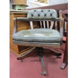 A Swivel Office Armchair, in green studded leather, on reeded legs.