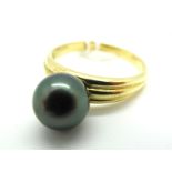 A Modern Black Pearl Dress Ring, between tapering reeded shoulders, stamped "750" (finger size Q).
