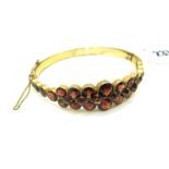 A XIX Century Style Garnet Set Bangle, graduated collet and clasp set to the front, hinged to snap