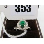 An Emerald and Diamond Cluster Ring, oval four claw set within border of brilliant cut stones,