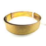 An Expandable Bangle, with allover engine turned design, stamped "9ct E A P" (15grams).