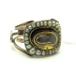 A Pearl and Enamel Mourning Ring, detailed to the centre with a glazed hairwork panel, between