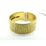 An 18ct Gold Wide Wedding Band, of uniform textured design (finger size P).