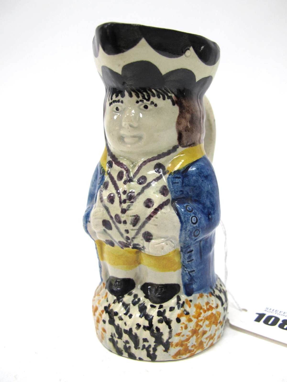 An Early XIX Century Prattware Toby Jug, in typical form wearing a blue jacket, spotted waistcoat,