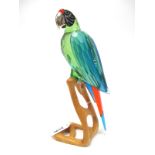 A Swarovski Crystal Paradise Bird Sculpture 'Macaw', on naturalistic wooden stand, 23.4cm high.