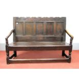 A XVII Century Joined Oak Settle, the top rail with carved lotus over five panel back, solid seat,