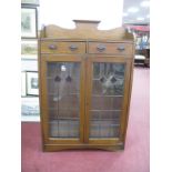 An Early XX Century Oak Book Cabinet, with shaped gallery, twin drawers over lead glazed doors, (
