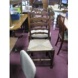 A Set of Six Oak Farmhouse Dining Chairs, with wavy ladder backs and rush seats.