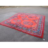 A Turkey Pattern Wool Carpet, circa 1920's, with blue and multicoloured motifs on red ground, 292