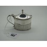 A Hallmarked Silver Lidded Mustard, (marks rubbed), of oval semi reeded form with scroll handle