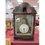 A Wall Clock, circa 1900, with enamel dial on painted lady, tin backing, with glass eyes (one