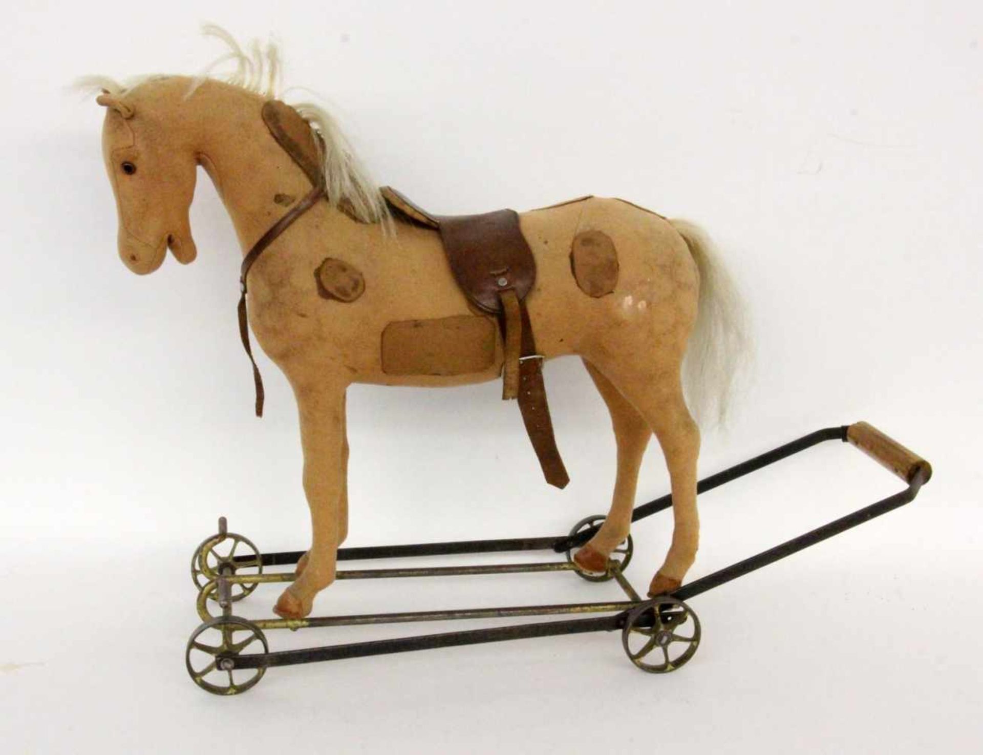 A HORSE ON WHEELS Old. Brown felt with leather saddle. On a metal frame for pushing. 48 cm