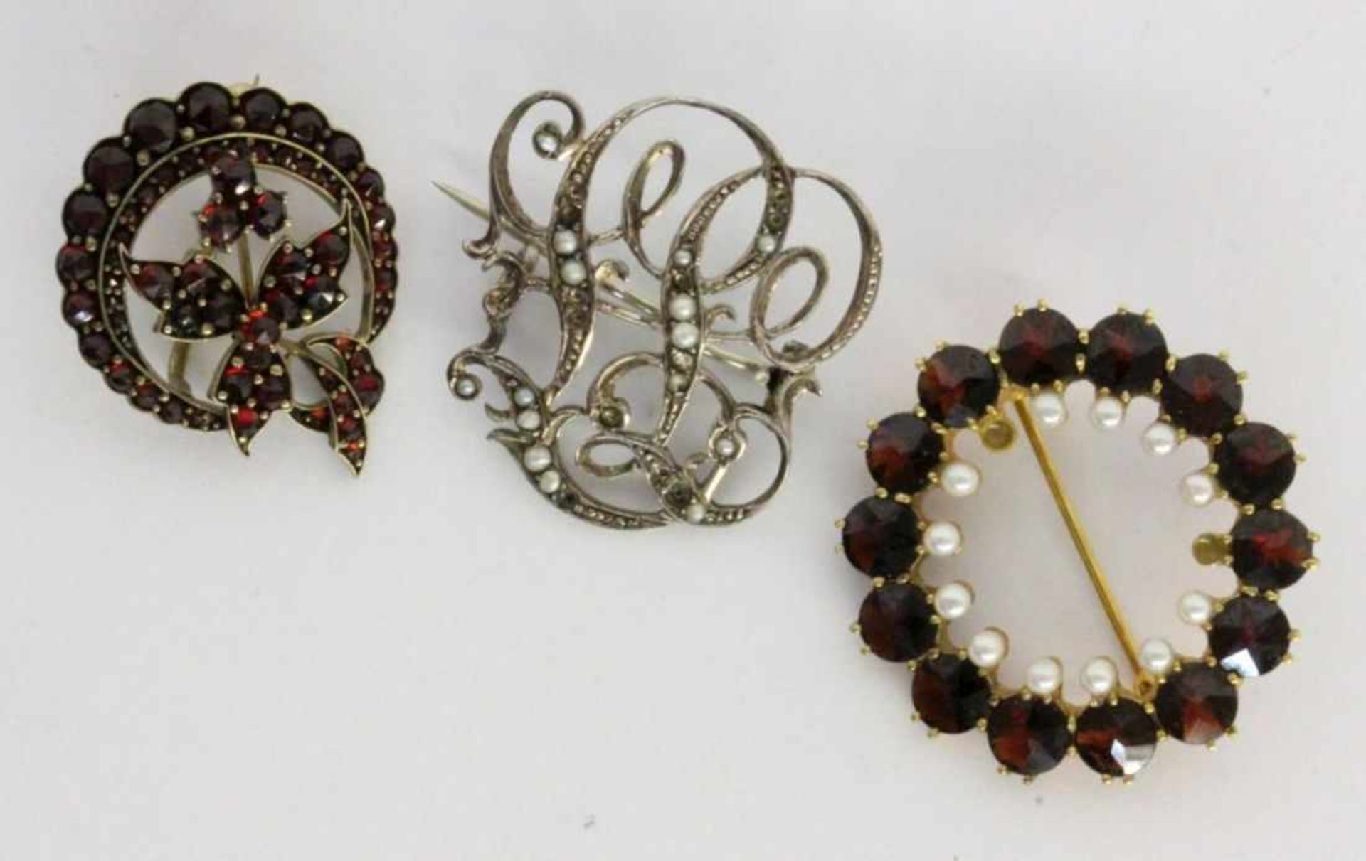 ''TWO GARNET BROOCHES Includes an Art Nouveau brooch with small pearls. Condition: some