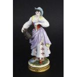 ''A FEMALE BIRD SELLER Volkstedt, Thuringia Colourfully decorated porcelain figure of a