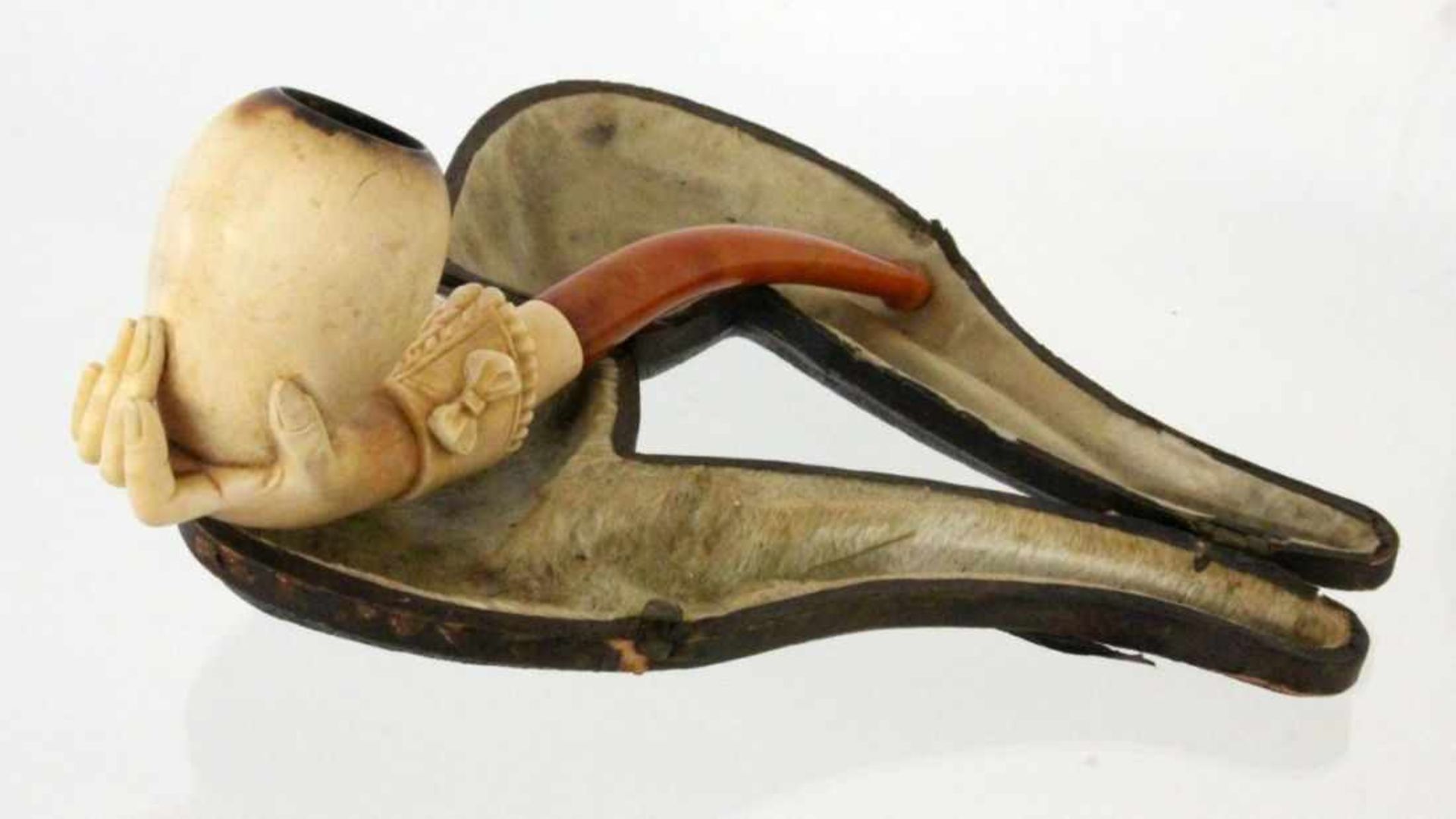 A MEERSCHAUM PIPE With carved hand. Mouthpiece amber (?). 15 cm long, in a case.
