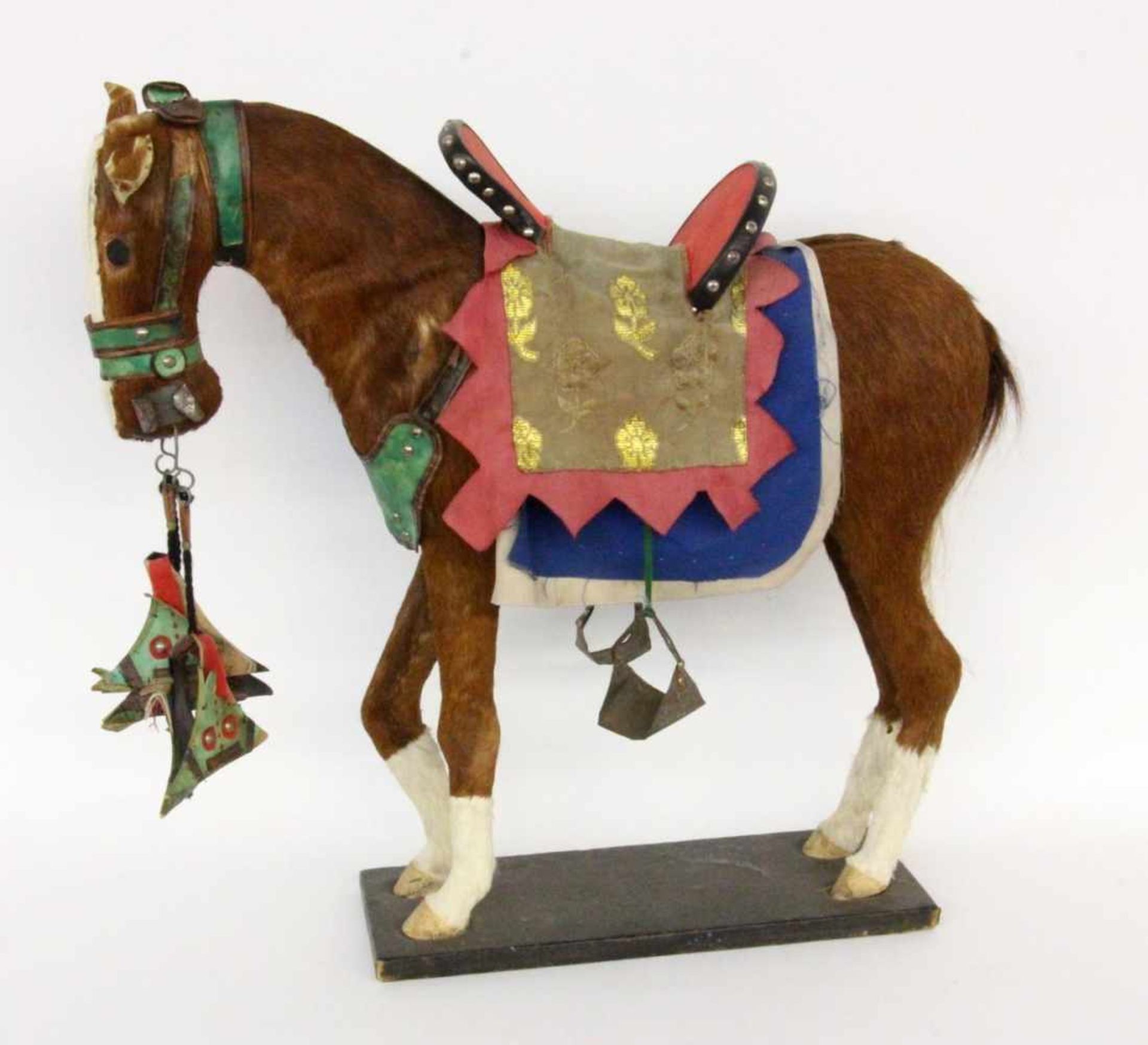 AN OLD ROCKING HORSE with brown fur and colourful saddle, 70 cm long, 65 cm high.