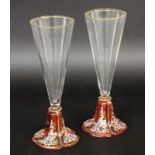 ''A PAIR OF CHAMPAGNE GLASSES Lobmeyr, Wien. Colourless cup on a ruby red stem with enamel