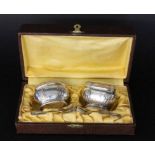A PAIR OF SALT BOWLSSilver-plated metal with gilt interior, glass inserts and 2 spoons. With case.