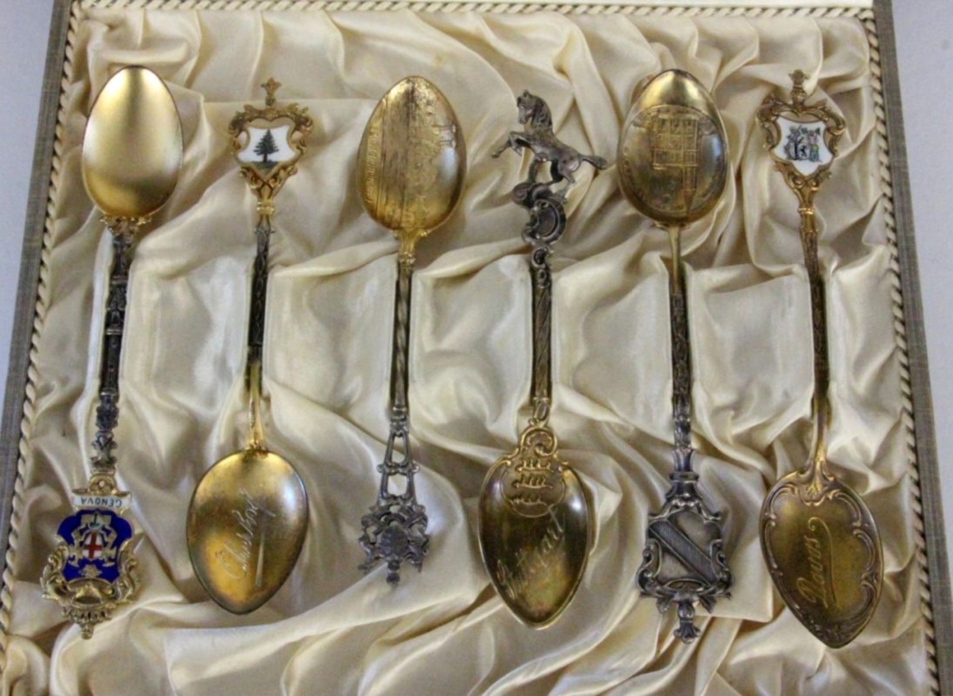 SIX SOUVENIR SPOONS Silver, partly gilded and partly with an enamelled coat of arms.