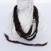 A GARNET NECKLACE 3 strands, with garnet beads measuring approx. 6 mm and cubes. 63 cm long.