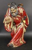 A SAMURAI Japan, 20th century Glazed ceramic figure of a Japanese warrior in a red coat.