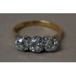 An 18ct gold and platinum three-stone Diamond ring, old brilliant cut stones in white gold coronet