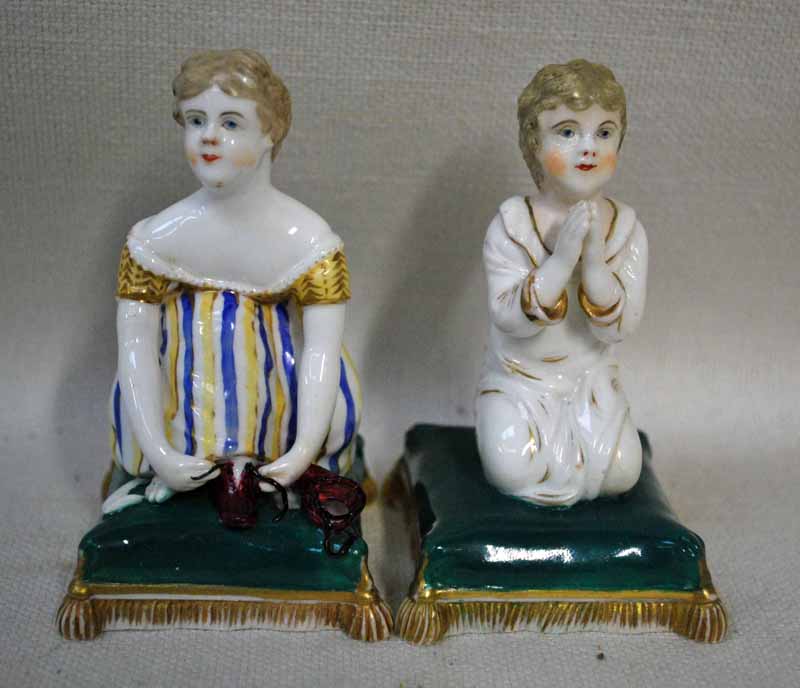 A Bloor Derby porcelain figure of a girl kneeling on a green cushion tying her shoe laces and a