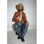 A large NAO figure as a Seated Sailor smoking a Pipe, brown jacket, blue trousers, C-27J to