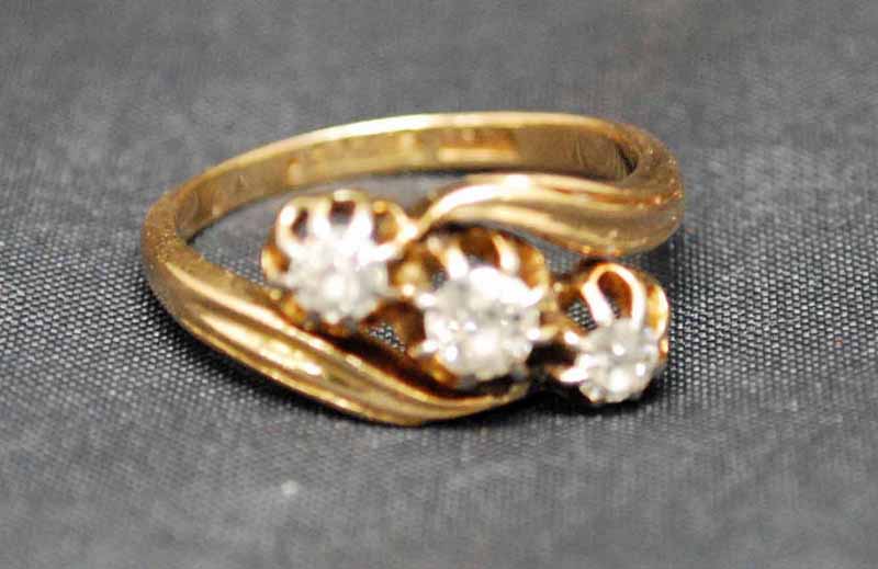 An 18ct gold three-stone diamond Cross Over Ring, the central stone approx 3.5mm diameter flanked by