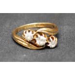 An 18ct gold three-stone diamond Cross Over Ring, the central stone approx 3.5mm diameter flanked by
