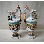 A pair of Capodimonte pottery Ewers, decorated in high relief with faun handles, cherubs, nymphs and