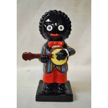 A Carlton Ware pottery model of a Golly playing a Banjo, left handed, colour trial piece, gold