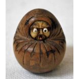 An early 20th century Japanese carved hardwood Okimono as a swaddled baby with circular ivory face